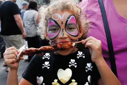 36th Annual Atlantic Antic; young girl with face painted at a fair; girl eating a kebab