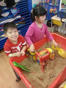 two children playing in appletree day care center's sandbox