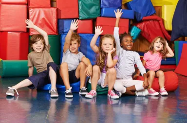38202025 – happy children raising their hands in gym of an elementary school