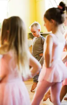 young boy in dance class surrounded by girl ballerinas