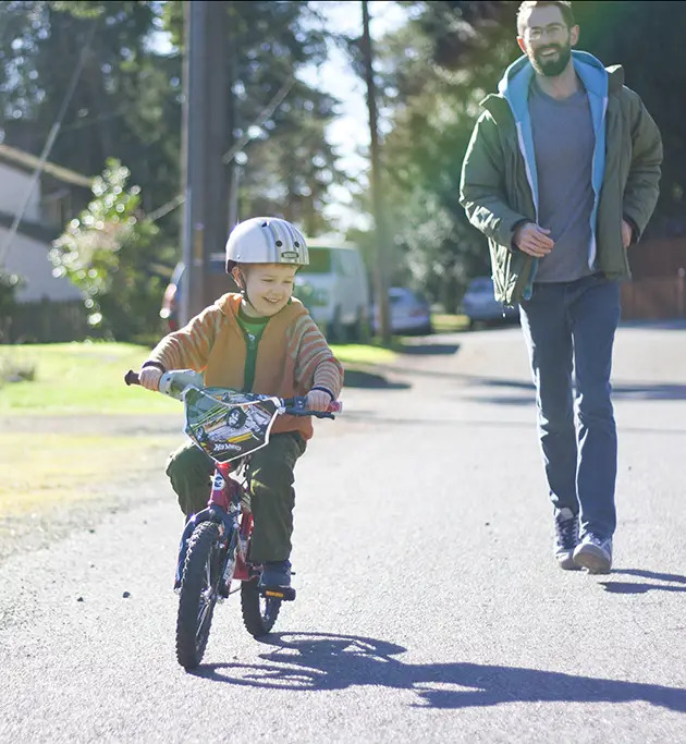 dad running after boy on bike