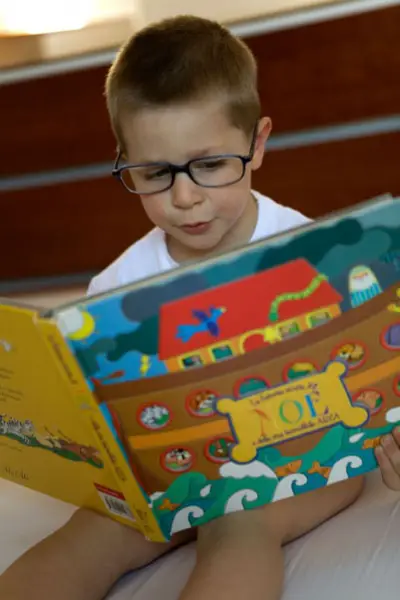 boy wearing glasses while reading a book