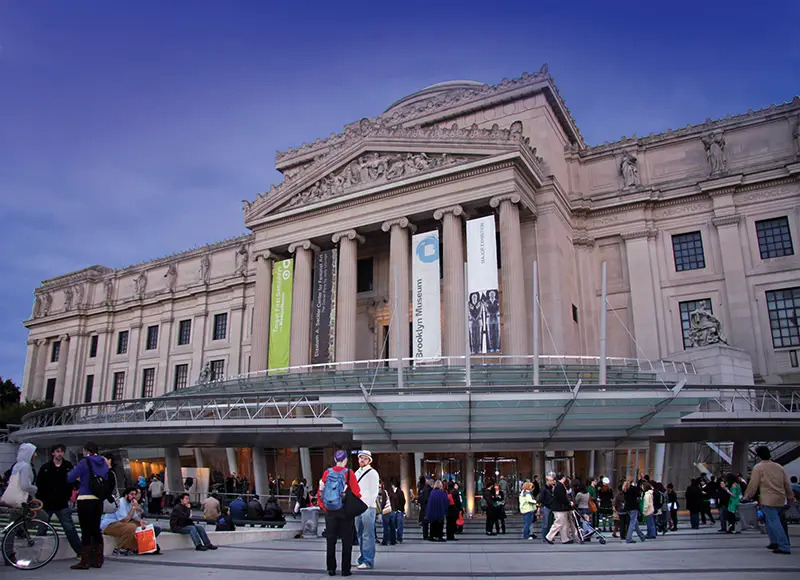 Exterior of Brooklyn Museum with people bustling around outside