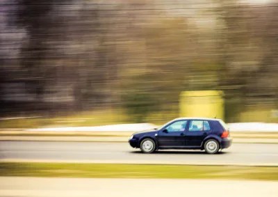 car driving along wooded street