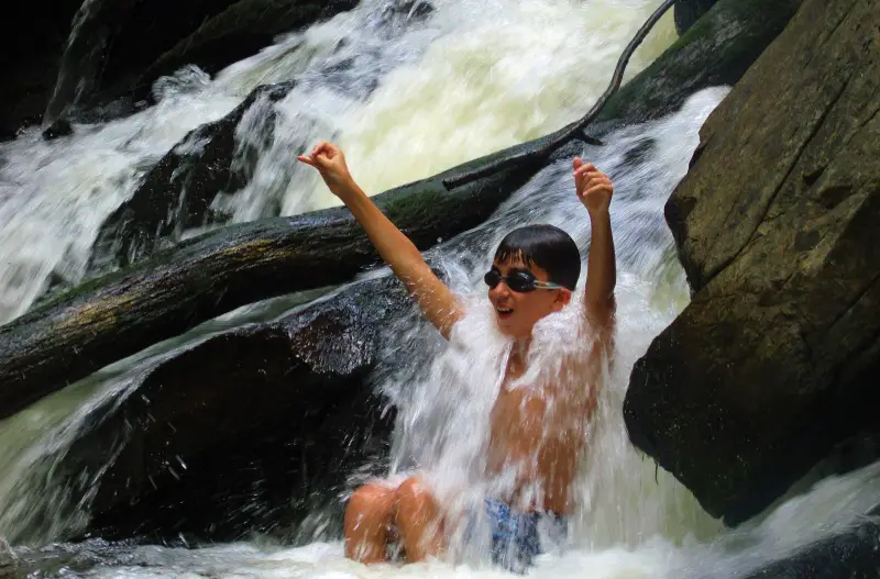child playing in waterfall
