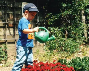 little boy watering the garden; child waters flowers