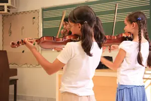children, girls playing violin; music class in school
