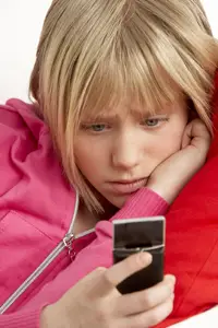 child reading a text message; young girl receives distressing text; cyber bullying