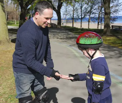 dad gives son a high five while rollerblading in the park