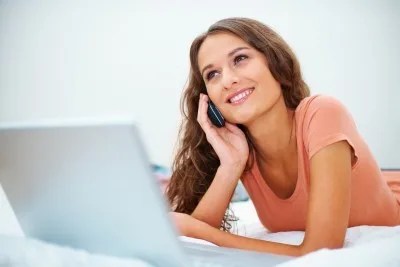 distracted woman using computer talking on cell phone