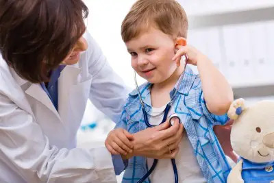 doctor listening to young boy's heart  