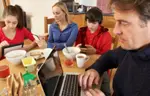 family on laptops phones at dinner