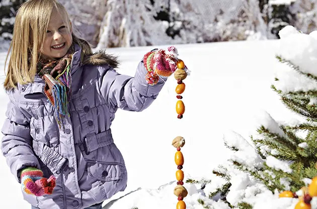 girl holding birdseed garland