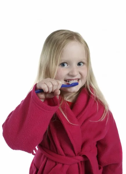 Girl brushing her teeth wearing a bath robe