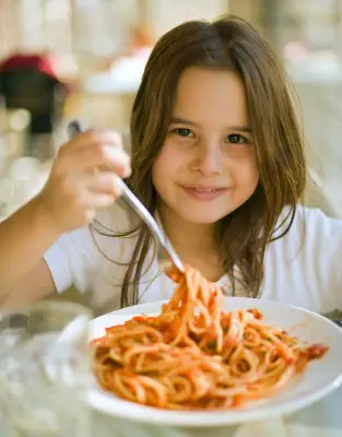 girl eating spaghetti in restaurant