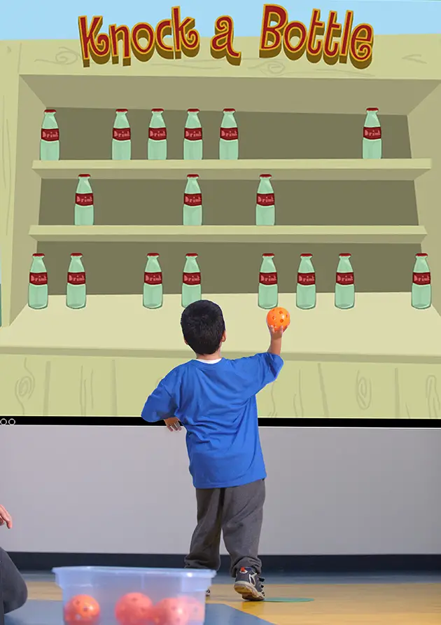 child throwing ball at interactive screen