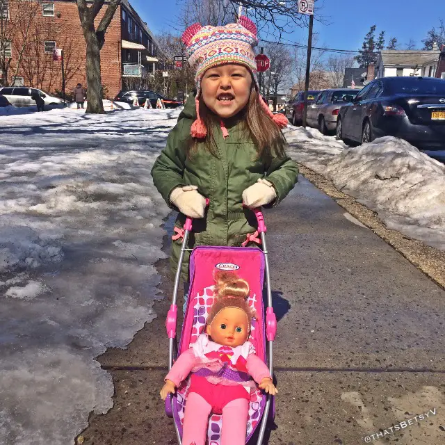 young girl pushing doll in stroller