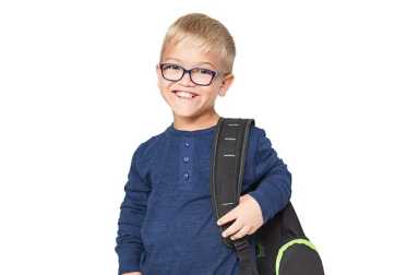 Smiling young boy with glasses and a blue long-sleeve shirt wearing a black backpack against a white background.