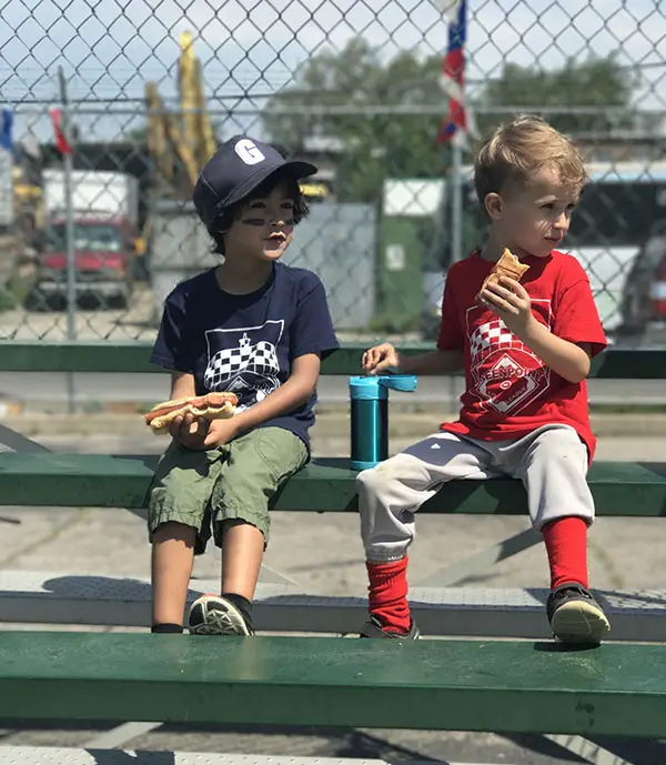 two young kids on bench at baseball field