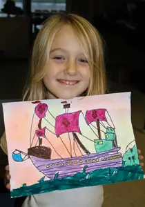 little girl holding her artwork; kids art class