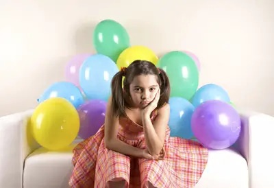 birthday girl looking sad at her party; sad young girl at a birthday party