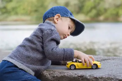 young boy playing with a toy car outside