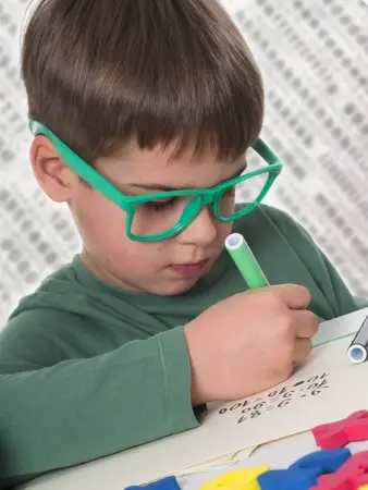 little boy wearing glasses doing homework