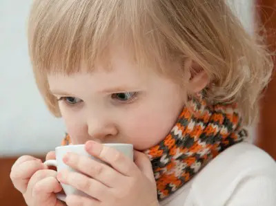 little girl with cold drinking hot liquid