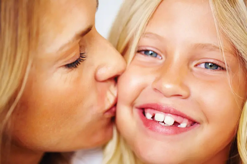 mother kissing daughter on the cheek