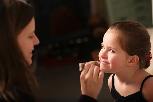 mother applying lip gloss on daughter