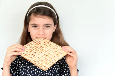 Jewish girl eating Matzo bread on Passover Jewish holiday