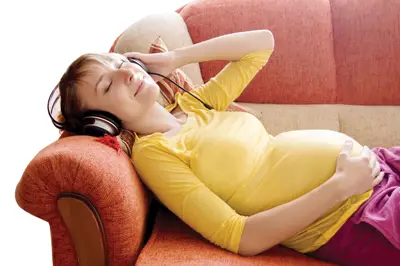 pregnant woman listening to music on the couch