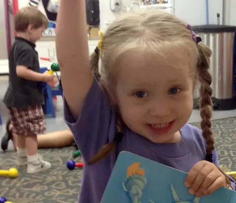preschool girl raises her hand to answer a question