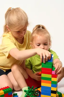 two little girls playing with blocks on the floor