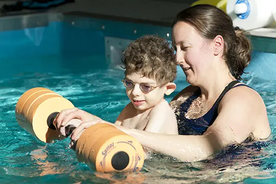 boy and therapist in doing aqua therapy