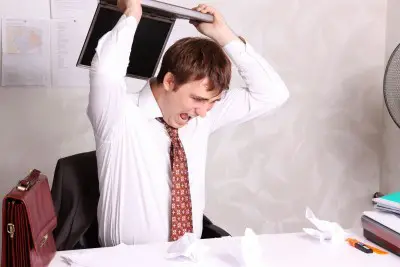 stressed man with laptop at work