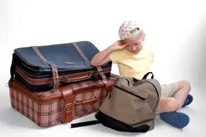 child packing for summer camp; child packing a suitcase