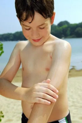 young boy applying sunscreen