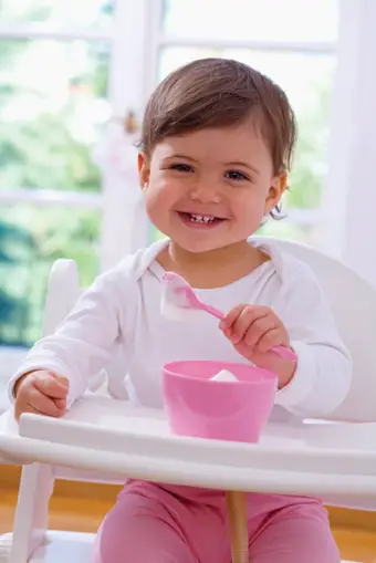 toddler in high chair eating yogurt
