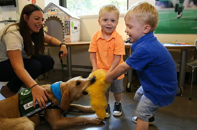 twin boys play with service dog