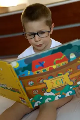child with glasses reading a book