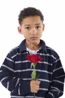 A young boy with short curly hair wearing a striped navy polo shirt holds a single red rose against a white background.