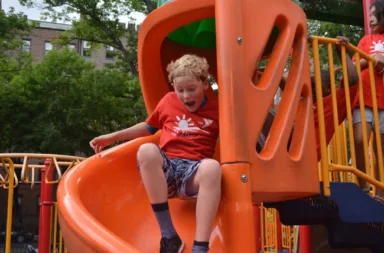 young-boy-going-down-slide-outside-playground