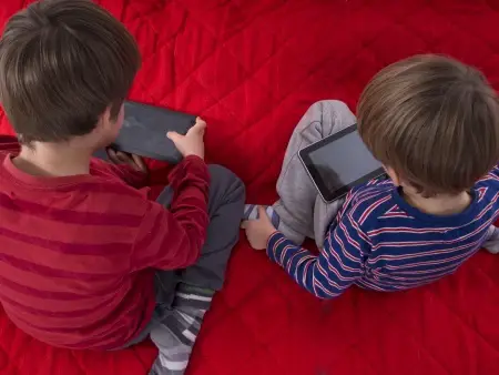 two young boys playing with tablets