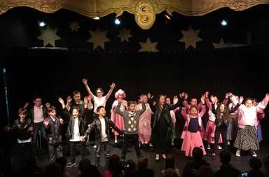 young-children-in-costume-performing-on-stage-with-audience