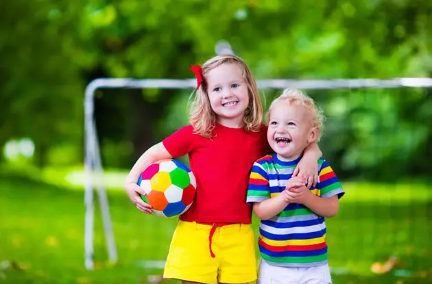 young girl and boy on soccer field with soccer ball