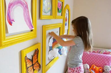 young_girl_hanging_art_in_frames_on_wall