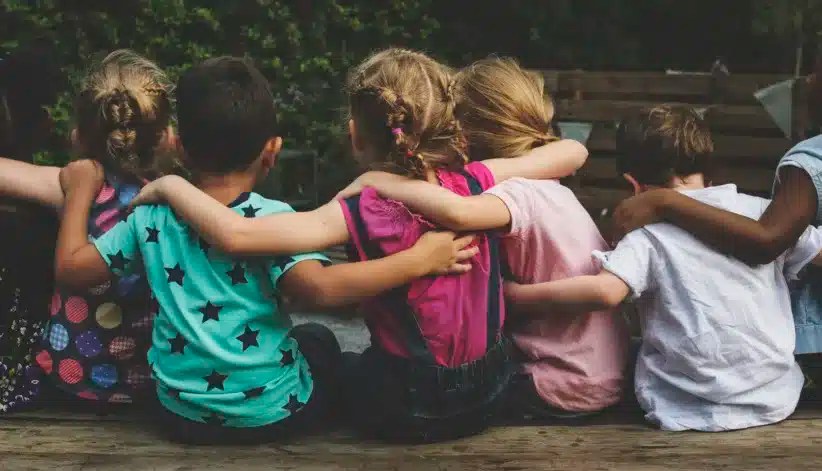 Group of kindergarten kids friends arm around sitting together