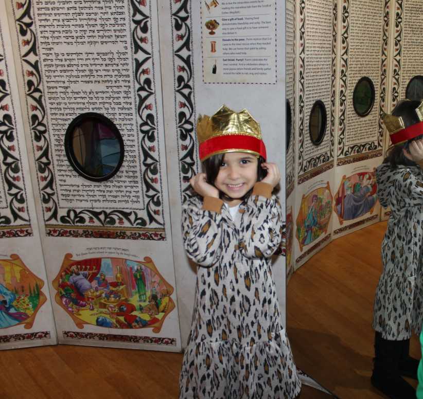 Child wearing a costume standing in front of a museum exhibit.
