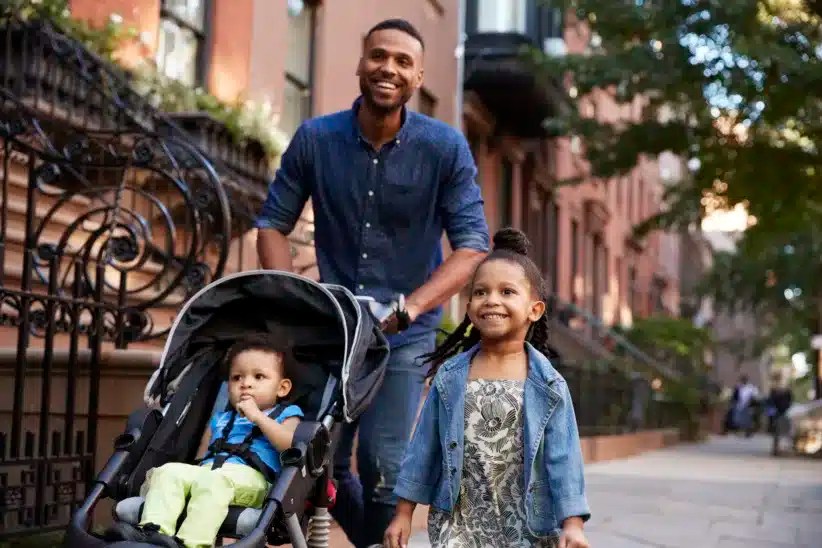 Father and two daughters taking a walk down the street, close up